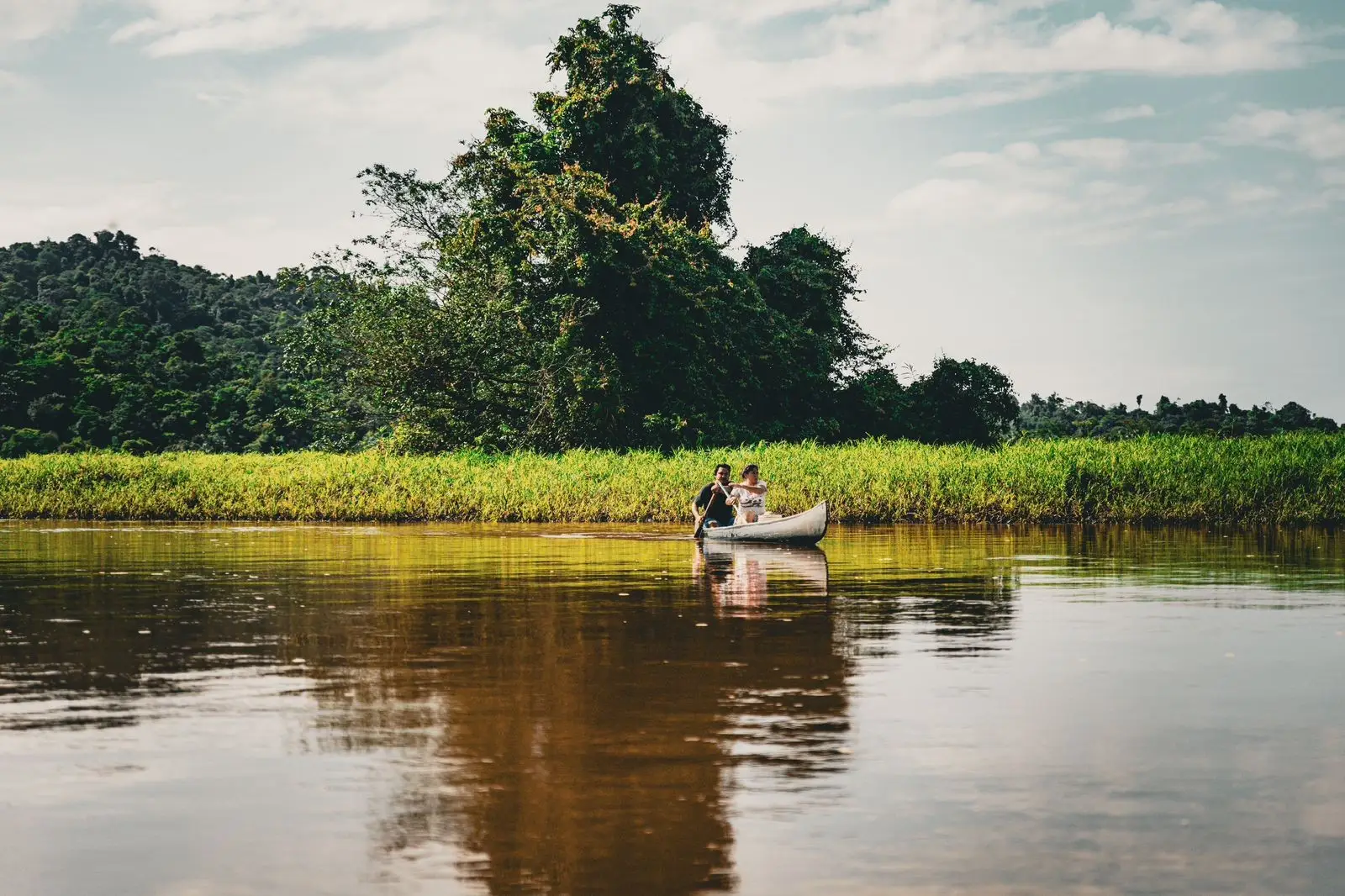 Dos personas se desplazan en bote por un río rodeado de vegetación